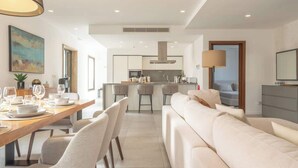 A modern kitchen with a central island, bar stools, and a dining area with a wooden table and chairs. - Sky villa penthouse, private pool | MIL by Homega (St. Julian's)