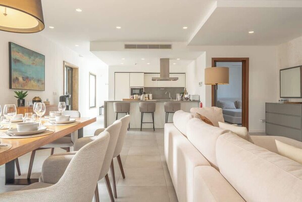 A modern kitchen with a central island, bar stools, and a dining area with a wooden table and chairs. - Sky villa penthouse, private pool | MIL by Homega (St. Julian's)
