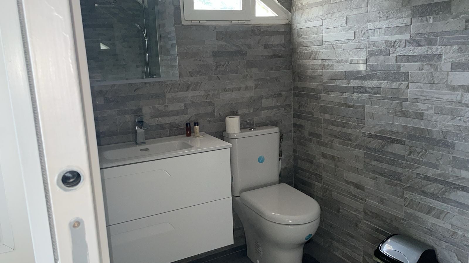 A bathroom with a white sink, toilet, and a window above the sink.