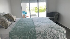 Un dormitorio con cama, una silla y vistas al exterior.