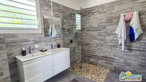 Un baño moderno con pared de piedra, cabina de ducha de vidrio y tocador con espejo.