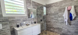 Un baño moderno con pared de piedra, cabina de ducha de vidrio y tocador con espejo.