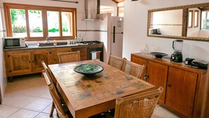 A kitchen with wooden cabinets, a dining table, and a large window.
