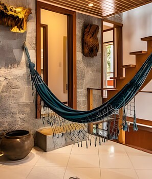 A hammock in a room with stone walls and a wooden staircase.