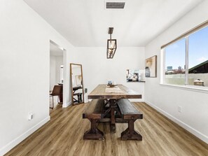 Ein Essbereich mit einem Holztisch und Bänken, weißen Wänden und einem Fenster mit Blick.