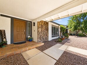 A house with a stone facade, a brown door, and a welcome sign.