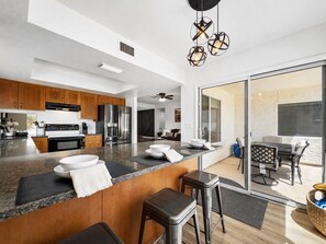 A modern kitchen with granite countertops, wooden cabinets, and a large island with stools.