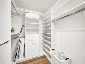 Ein begehbarer Kleiderschrank mit offenen Regalen, Schubladen und einer Kleiderstange.