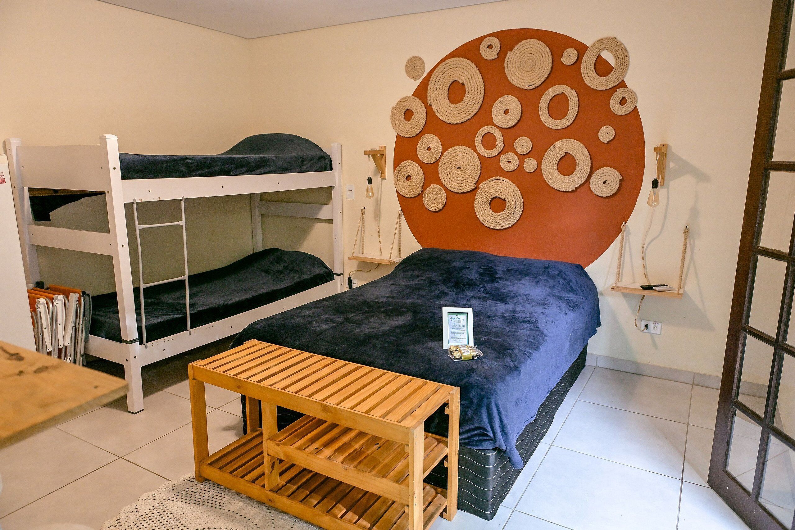 A dormitory room with bunk beds, a wooden table, and a wall with circular patterns.