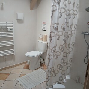 Une salle de bain avec des toilettes, un rideau de douche, un porte-serviettes et une affiche accrochée au mur.