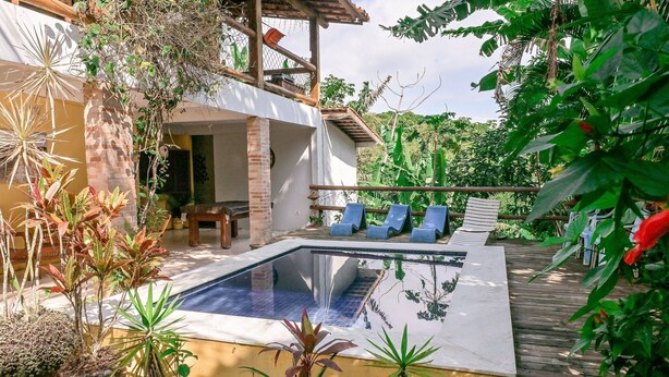 A pool area with a wooden deck, lounge chairs, and potted plants.