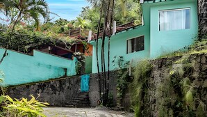 A stone pathway leading to a turquoise house with a window and a blue gate.