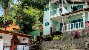 A pool area with a stone wall and a building with a balcony.