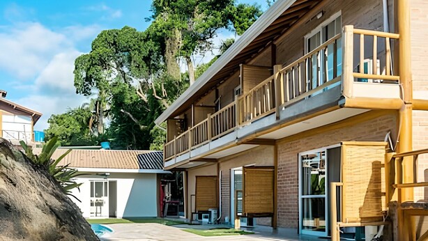 A two-story building with a balcony, large windows, and a covered outdoor area. - Recanto da Feiticeira | Double suite with balcony (Ilhabela)