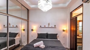 Une chambre d’hôtel avec un grand lit, un lustre et un miroir.