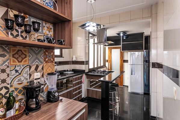 A modern kitchen with a central island, a built-in stove, and a refrigerator.