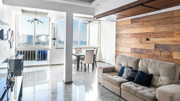 Un salon moderne doté d’une grande fenêtre, d’un mur d’accent en bois, d’un canapé beige et d’un coin repas.