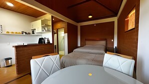 Una habitación de hotel compacta con cama, una pequeña mesa y kitchenette.