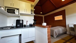 Habitación pequeña con kitchenette, una cama y un ventanal.