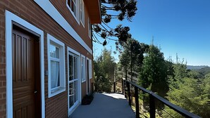 A residential building with a balcony overlooking a lush green landscape. - Saint Louis | Studio 3 to 4 min from the center (Campos do Jordão)