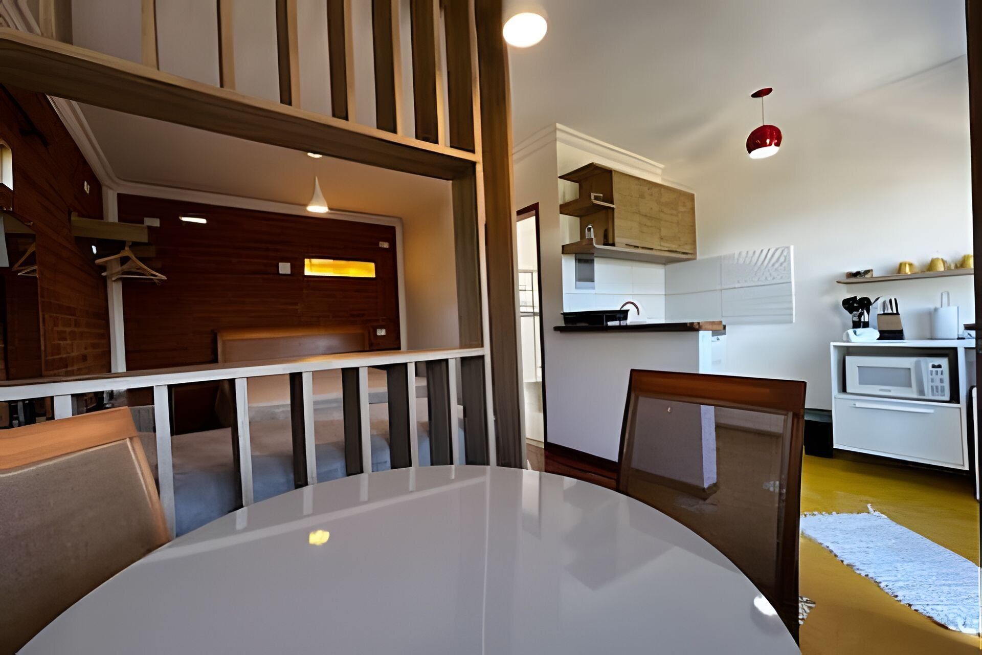 Un coin repas avec une table ronde et des chaises, une cuisine en arrière-plan et un escalier menant à un niveau supérieur.