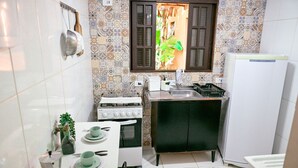 Una cocina compacta con estufa a gas, horno, pileta y heladera.