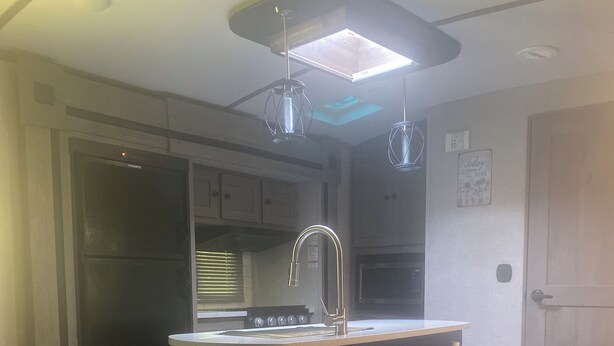 Une cuisine moderne dotée d’un îlot central, d ’un robinet en acier inoxydable et de luminaires suspendus.