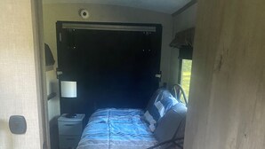 Une chambre à coucher avec un lit, une table de chevet, une lampe et une fenêtre.