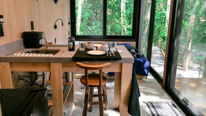 Une cuisine moderne avec un plan de travail en bois, un évier et une fenêtre donnant sur une forêt.