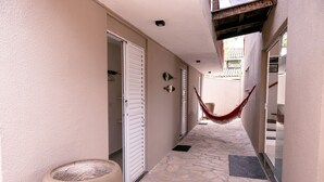 A corridor with a hammock, a large planter, and a door leading to a room. - Ponta do Sol | 4 suítes, piscina e churrasqueira (Ilhabela)