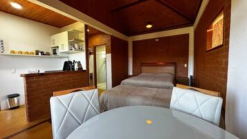 Quarto compacto com cama, cozinha compacta e área de refeições.
