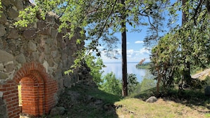 Una struttura in pietra con arco in mattoni, immersa nel verde e affacciata su un lago tranquillo.