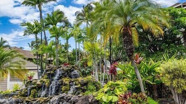 A tropical garden with a waterfall, palm trees, and a house. - Grand Champions (Kihei)