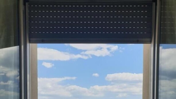 Un balcon avec deux chaises et une table, donnant sur une plage sous un ciel dégagé.