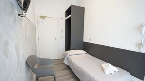 Une petite chambre moderne, équipée d’un lit simple, d’une chaise et d’une armoire.