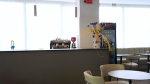 Un hall d’hôtel moderne comprenant un comptoir d’accueil, un espace salon et un distributeur automatique.