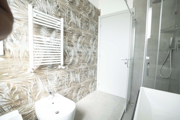A modern bathroom with a white sink, a glass shower enclosure, and a wall with a leaf pattern. - Hotel Giannini (Rimini)