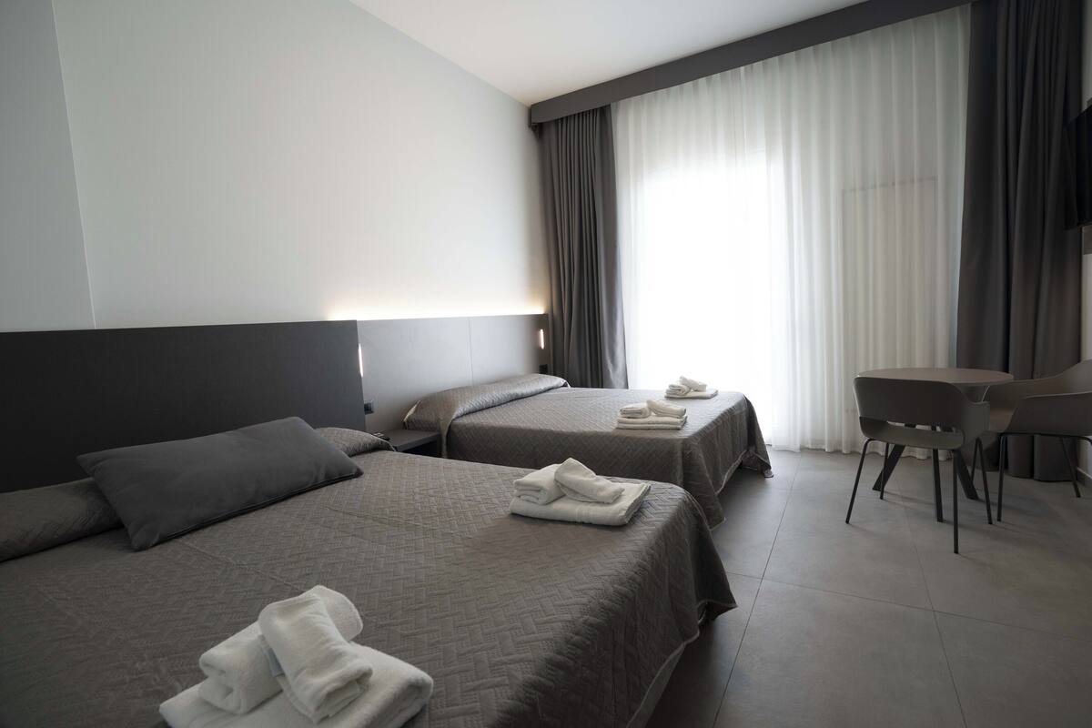 A hotel room with two beds, a desk, and a chair.