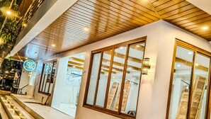 A modern building with a wooden ceiling, large windows, and a marble staircase.