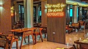 A restaurant interior with wooden furniture, a neon sign, and a view of the outside.