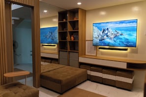 Una sala de estar moderna con un televisor de pantalla plana grande, un mueble de entretenimiento de madera, un sofá y una mesita.