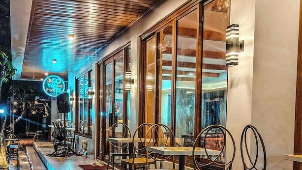 A restaurant with wooden flooring, metal-framed chairs, and large windows.