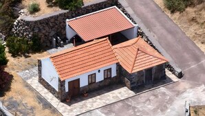Un edificio de dos plantas con techo de tejas rojas, paredes de piedra y un patio empedrado.