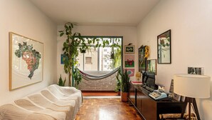 A room with a hammock, a desk with a typewriter, and a bed with a striped blanket. - Copacabana 2 quartos na quadra da praia. (Rio de Janeiro)