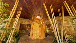 Una cabaña de bambú con una puerta central y un pasillo de madera.
