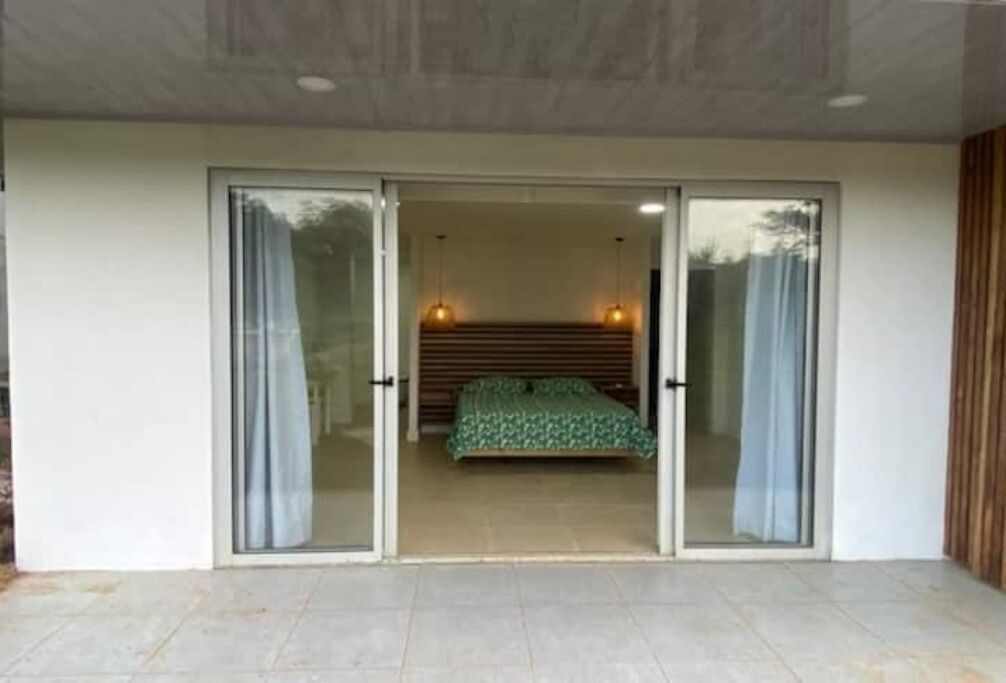 A bedroom with a bed, sliding glass doors, and two pendant lights.