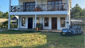 A two-story building with a balcony, a golf cart, and a lawn in front.