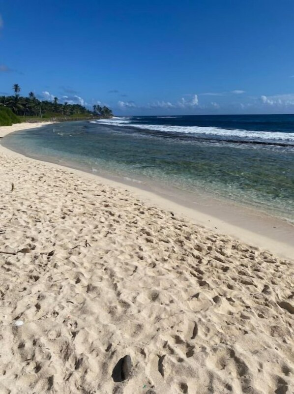 A sandy beach with clear water and a clear sky.