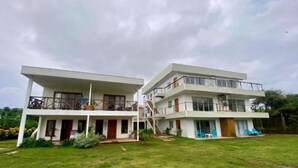 A two-story building with a flat roof and a balcony on the upper floor.