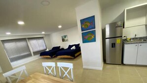 A compact living space with a dining area, two beds, a kitchenette, and artwork on the walls. - Savannah Inn 204 Studio AC,Wifi,TV, (San Andrés y Providencia)
